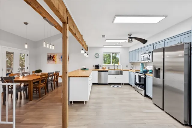 a large white kitchen with lots of counter space a sink appliances and a dining table