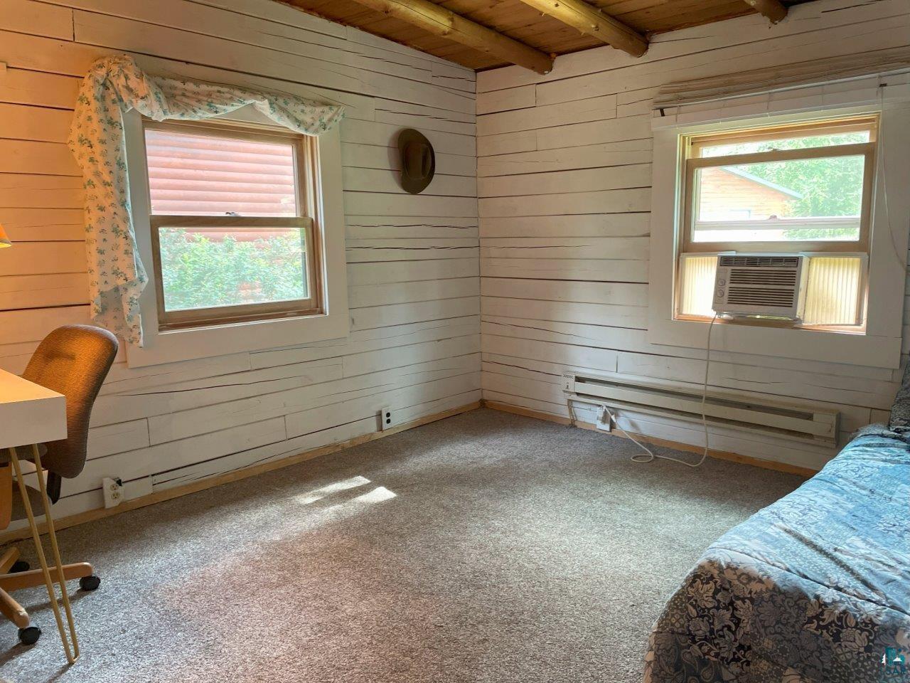3420 Dewees Road Babbitt, MN 55706 - Photo 20 of 58 Carpeted bedroom featuring wooden walls, a baseboard heating unit, a wooden ceiling with exposed beams, and cooling unit