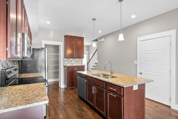 a kitchen with a sink a counter top space stainless steel appliances and wooden floor