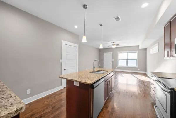 a kitchen with granite countertop a sink dishwasher and a wooden floor