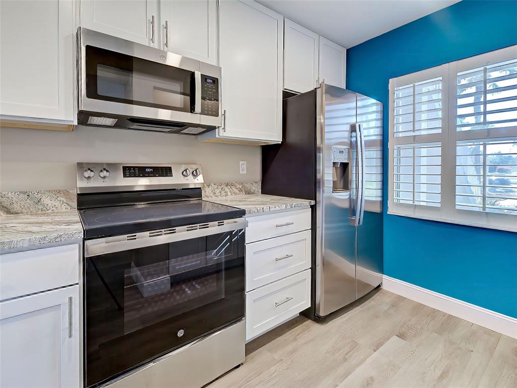429 Cerromar Lane, Unit 352 Venice, FL 34293 - Photo 11 of 47 a kitchen with stainless steel appliances a stove microwave and cabinets