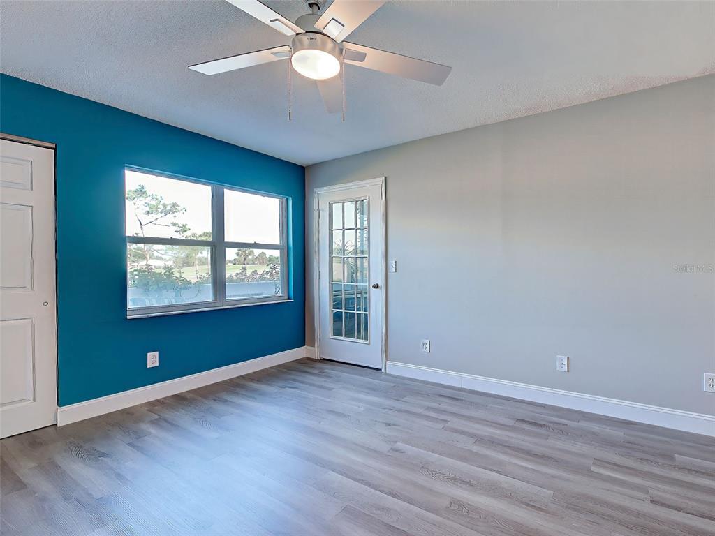 429 Cerromar Lane, Unit 352 Venice, FL 34293 - Photo 18 of 47 an empty room with wooden floor chandelier fan and windows