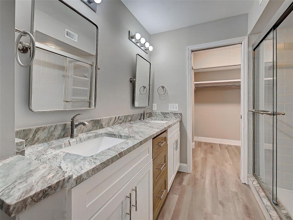 429 Cerromar Lane, Unit 352 Venice, FL 34293 - Photo 27 of 47 a bathroom with a granite countertop sink a mirror and a shower