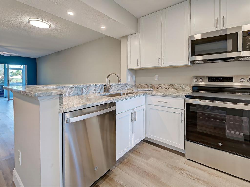 429 Cerromar Lane, Unit 352 Venice, FL 34293 - Photo 9 of 47 a kitchen with stainless steel appliances granite countertop a stove a microwave and white cabinets