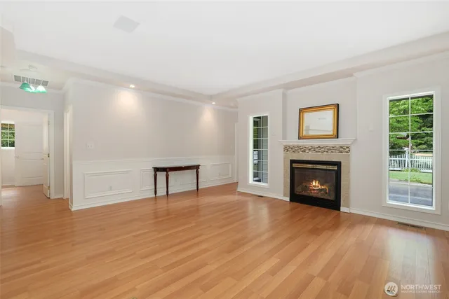 a view of an empty room with wooden floor fireplace and a window