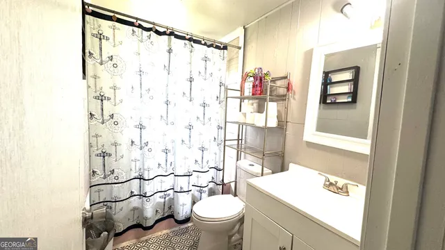 a bathroom with a sink a toilet and shower curtain
