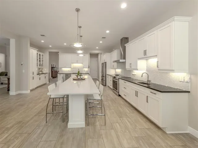 a kitchen with stainless steel appliances kitchen island granite countertop a sink a stove and a wooden floors