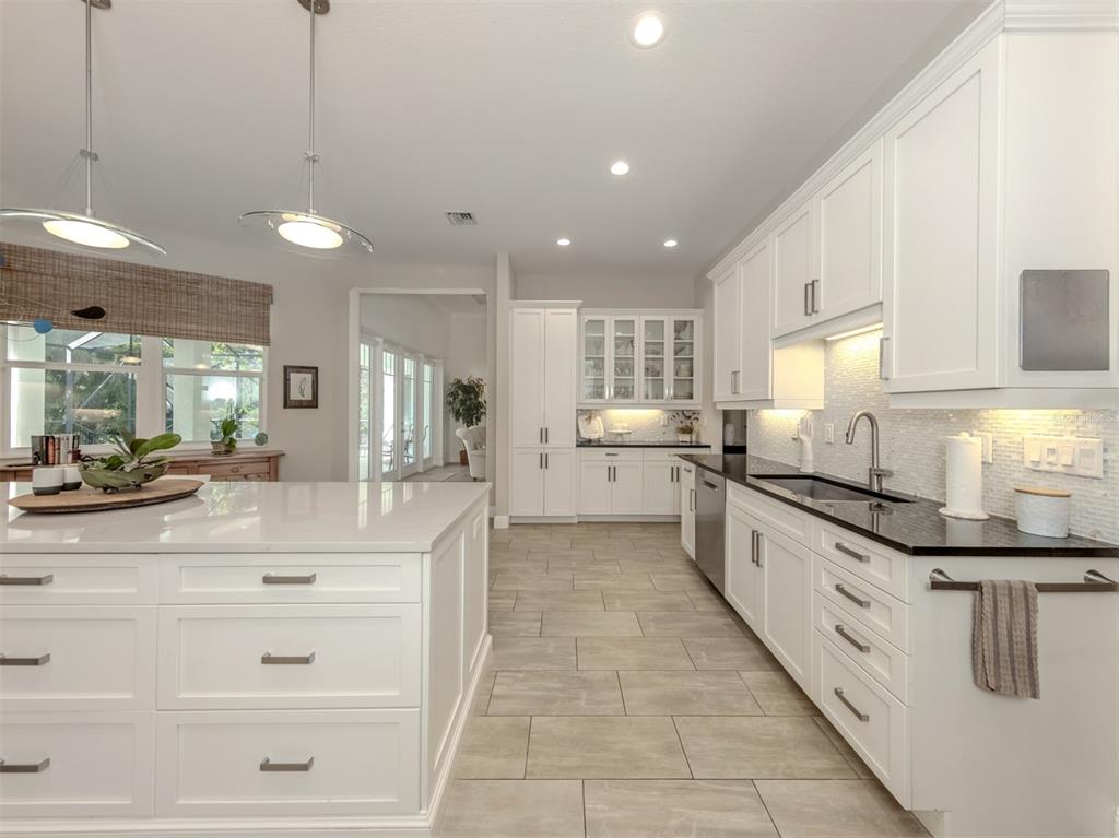 332 Pensacola Road Venice, FL 34285 - Photo 14 of 56 a large white kitchen with kitchen island a sink a counter space and stainless steel appliances