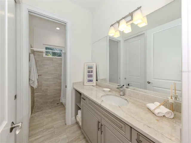 a bathroom with a granite countertop sink a large mirror and a shower