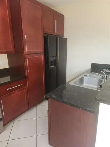 a kitchen with granite countertop a refrigerator and a sink