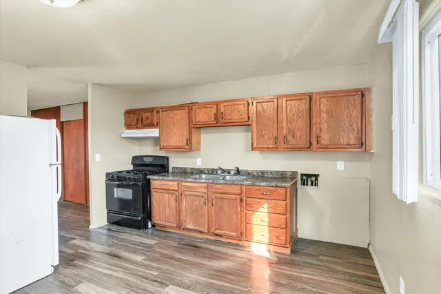 a kitchen with granite countertop a refrigerator stove top oven and sink