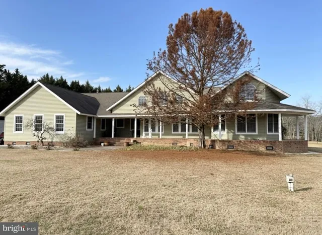 a front view of a house with a yard and large trees