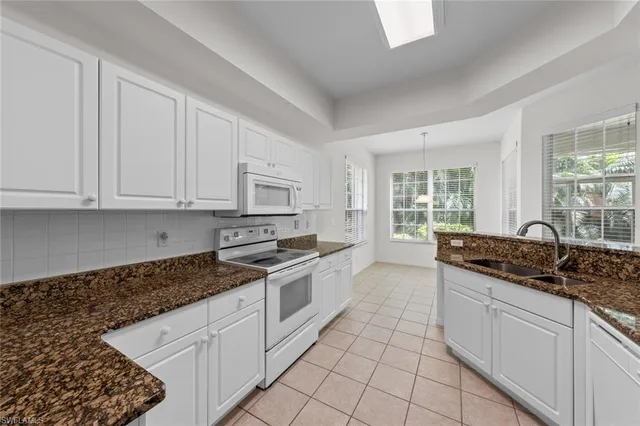 a kitchen with granite countertop white cabinets and white appliances