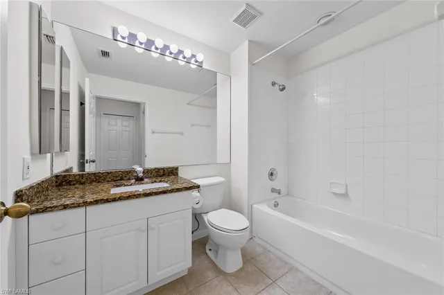 a spacious bathroom with a granite countertop sink a toilet mirror and a bathtub