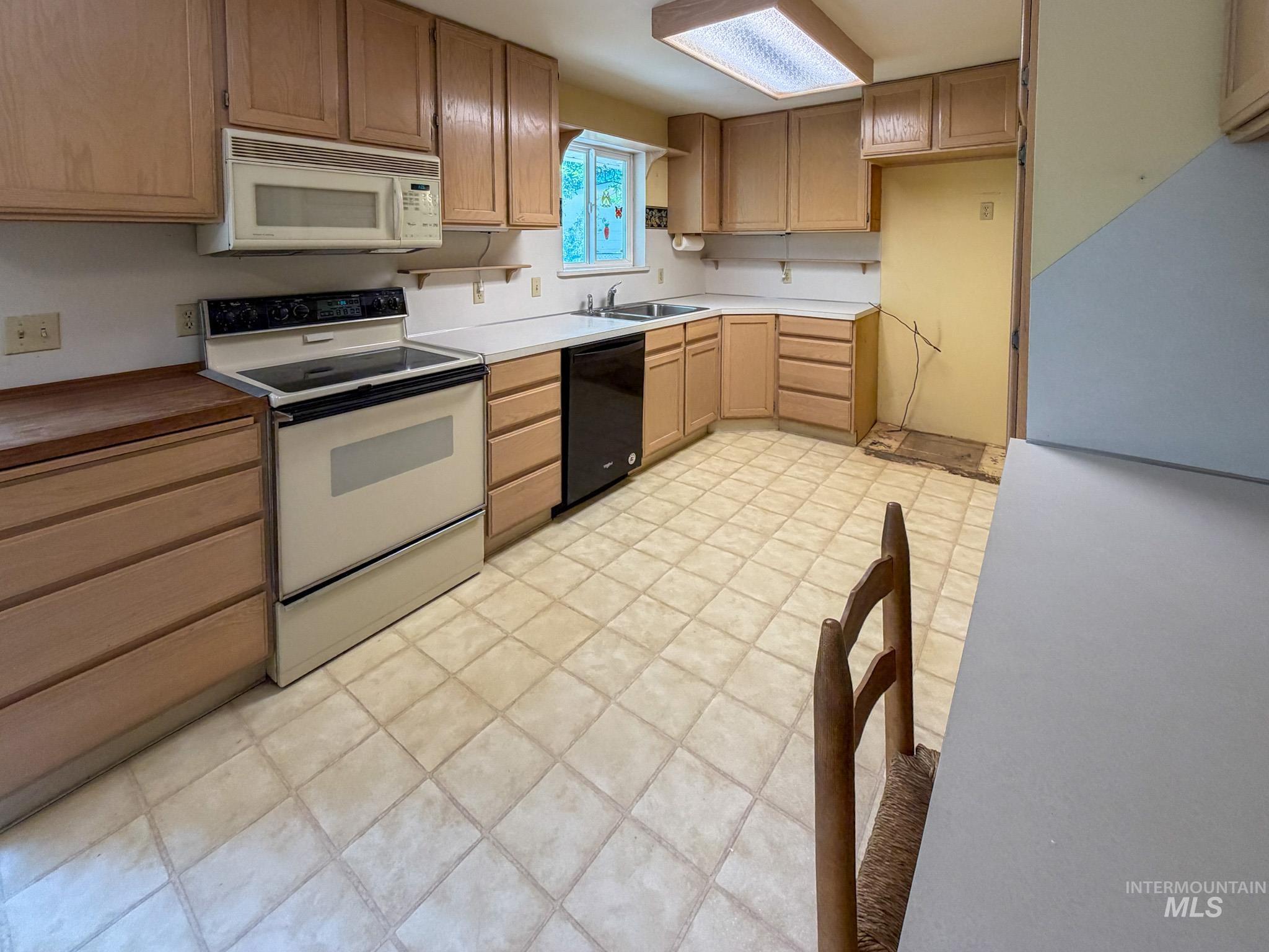 1924 H Street Rupert, ID 83350 - Photo 8 of 13 Kitchen featuring light wood cabinetry, a white electric range, an over-the-range microwave, a black built-in dishwasher, and a double basin sink