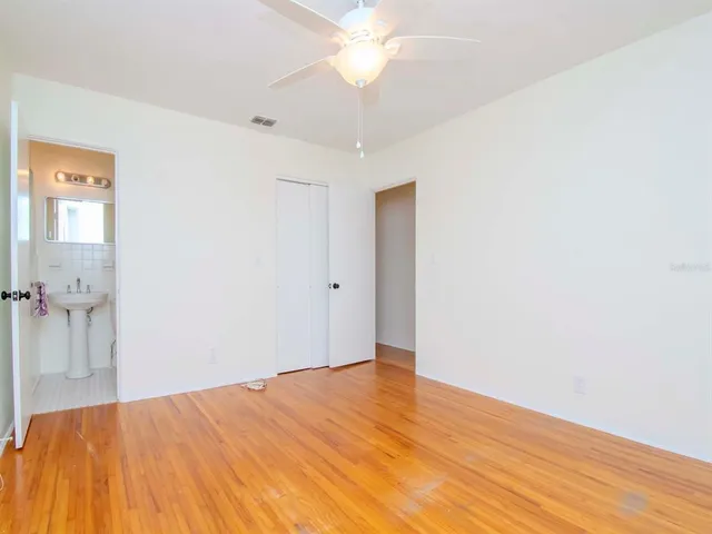 a view of a bedroom with wooden floor and a ceiling fan
