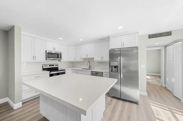 a kitchen with stainless steel appliances a white cabinets wooden floor and a sink