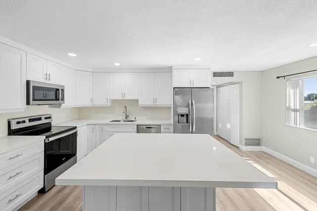 a kitchen with a refrigerator stove top oven and sink