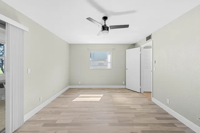a view of empty room with wooden floor and ceiling fan