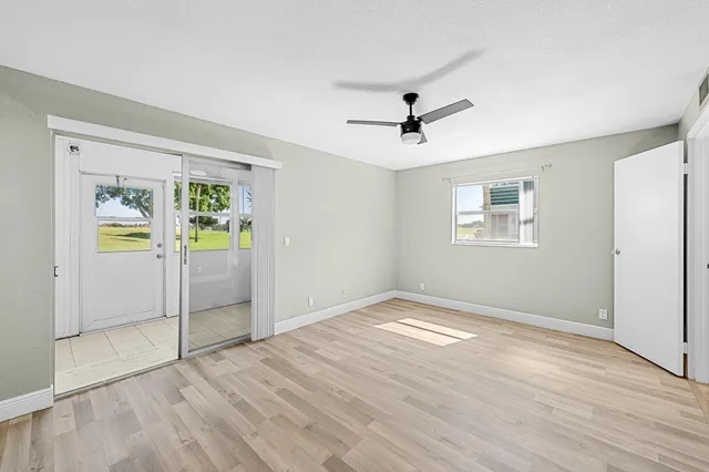 a view of empty room with wooden floor and ceiling fan