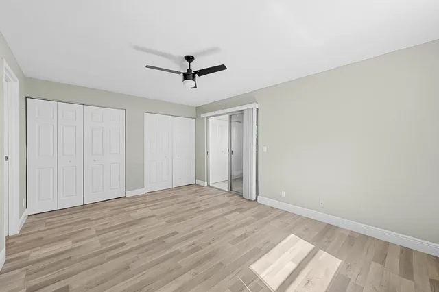 a view of empty room with wooden floor and ceiling fan