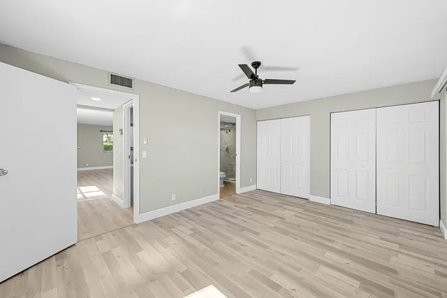 a view of empty room with wooden floor and ceiling fan