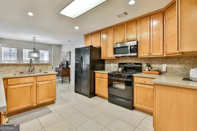 a kitchen with stainless steel appliances granite countertop a refrigerator sink and stove