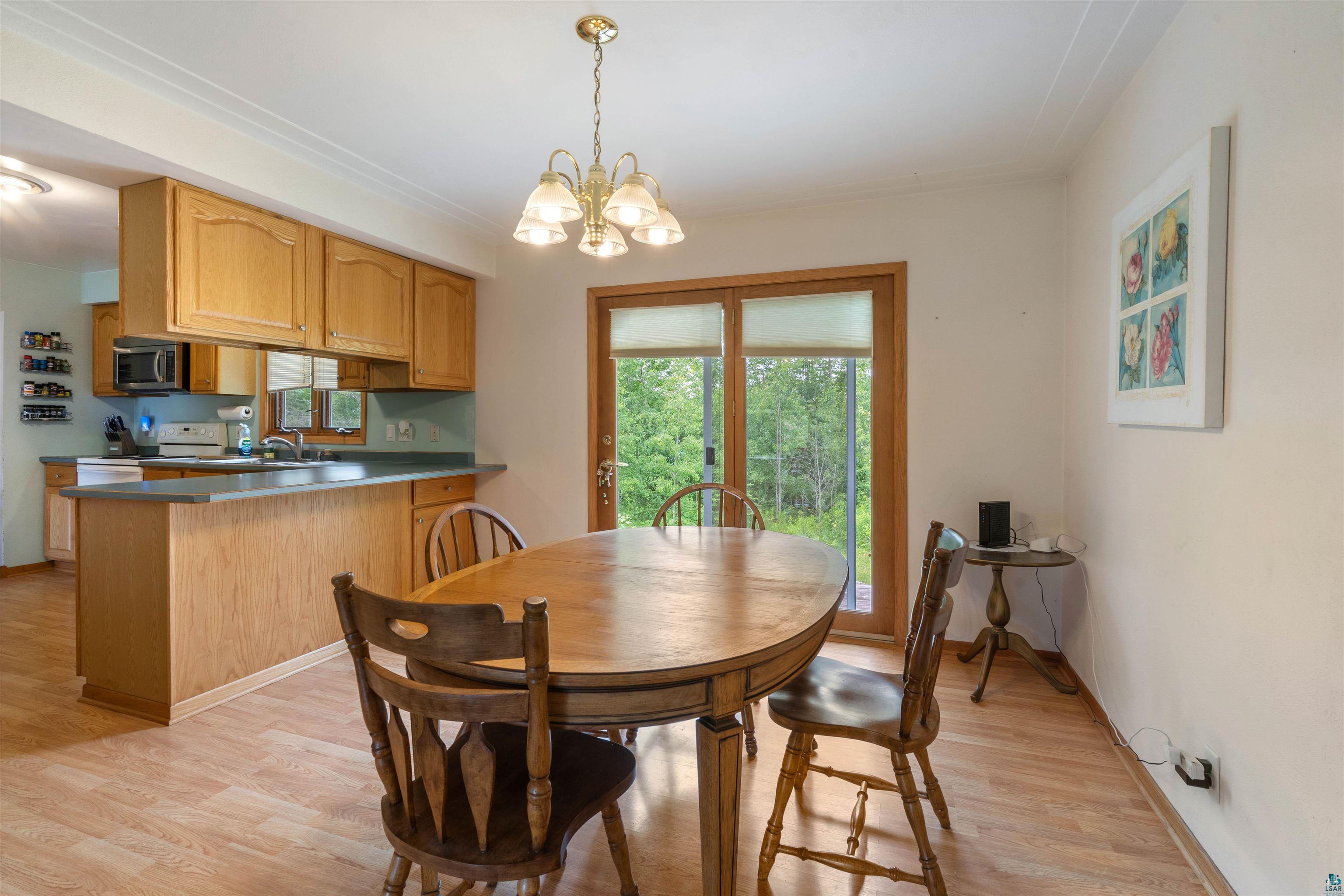 3711 Getchell Road Hermantown, MN 55811 - Photo 10 of 31 Dining area featuring wood-finish flooring, a brass chandelier, and sliding glass doors