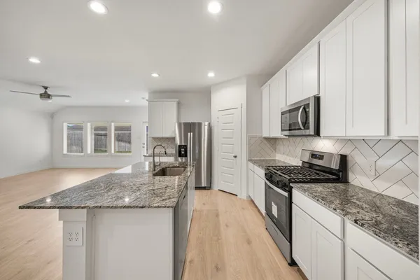 a kitchen with granite countertop kitchen island stainless steel appliances a stove sink microwave and cabinets