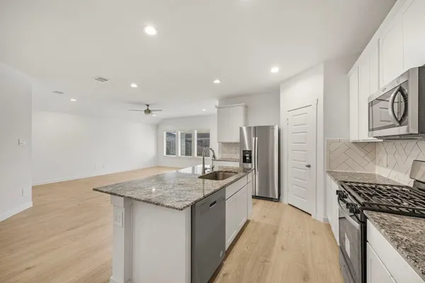 a kitchen with stainless steel appliances granite countertop a sink stove and refrigerator