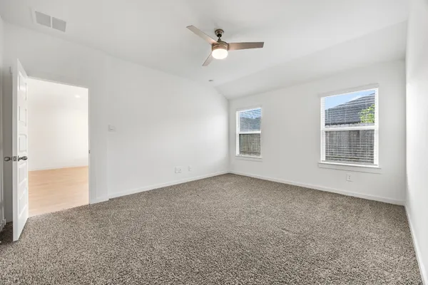 an empty room with windows and ceiling fan