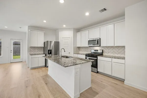 a kitchen with granite countertop a sink stove and refrigerator