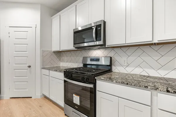 a kitchen with granite countertop white cabinets and stainless steel appliances