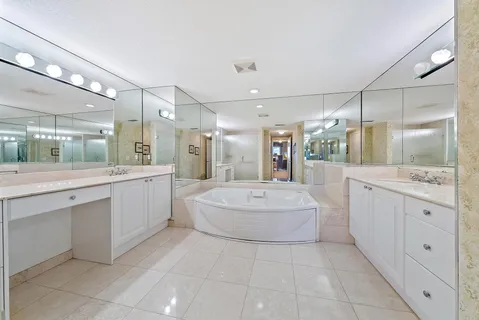a large white bathroom with a large mirror vanity shower and bathtub