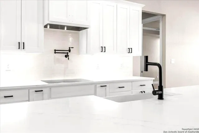 an empty room with wooden floor chandelier and windows