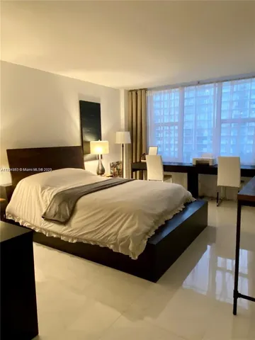 a bedroom with a bed and large windows