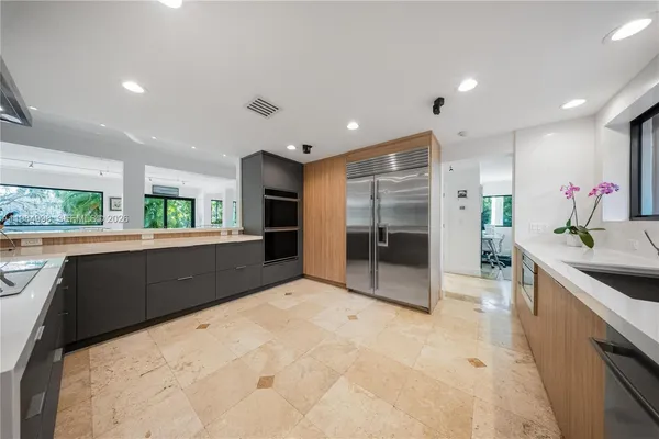 a large kitchen with stainless steel appliances a large counter top a stove a sink and a refrigerator