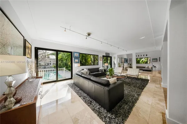 a living room with furniture large windows and flat screen tv