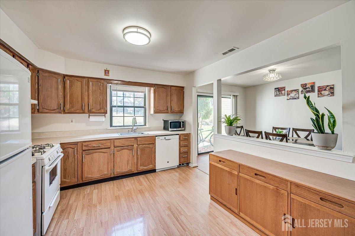 602 Maplecrest Road Edison, NJ 08820 - Photo 20 of 42 a large kitchen with kitchen island granite countertop a stove a sink dishwasher and white cabinets with wooden floor