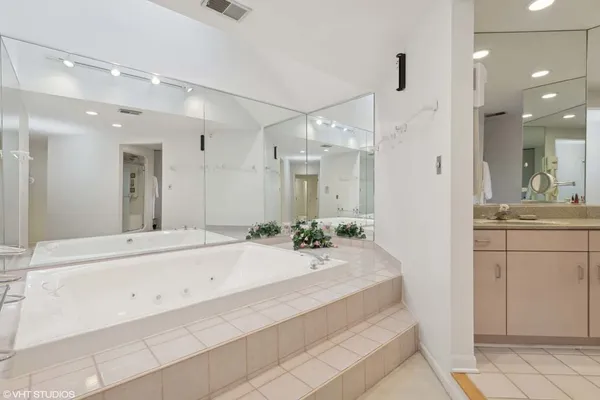 a bathroom with a sink vanity granite tub shower and a mirror