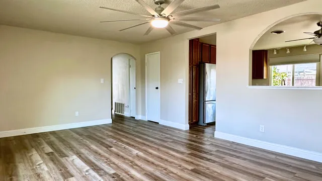 a view of an empty room with window and wooden floor
