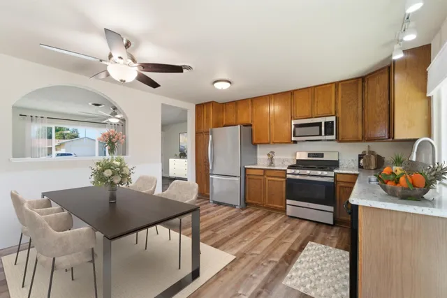 a kitchen with stainless steel appliances granite countertop a refrigerator a stove top oven a sink dishwasher and white cabinets with wooden floor