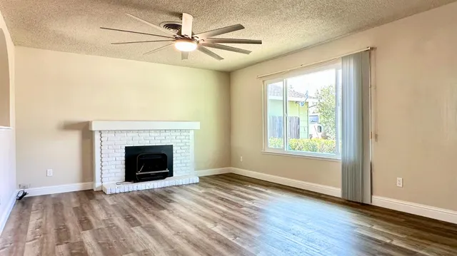 an empty room with wooden floor fireplace and windows