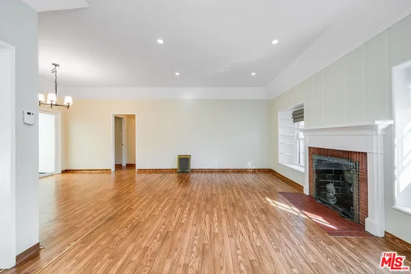 an empty room with wooden floor and fireplace