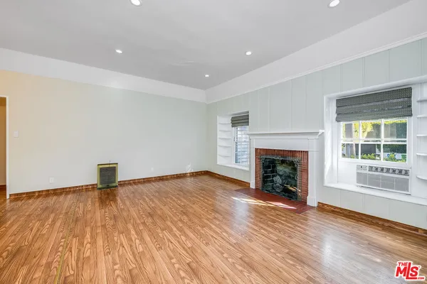 a view of empty room with wooden floor and fireplace