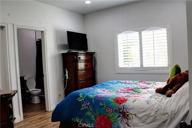a bedroom with a bed and flat tv screen on the dresser