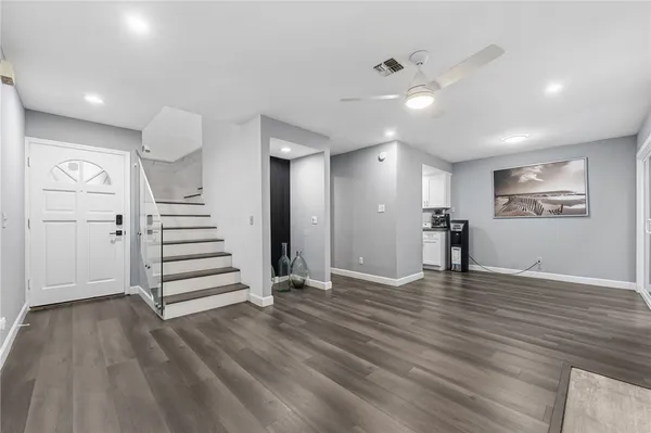 a view of an empty room with wooden floor and a ceiling fan