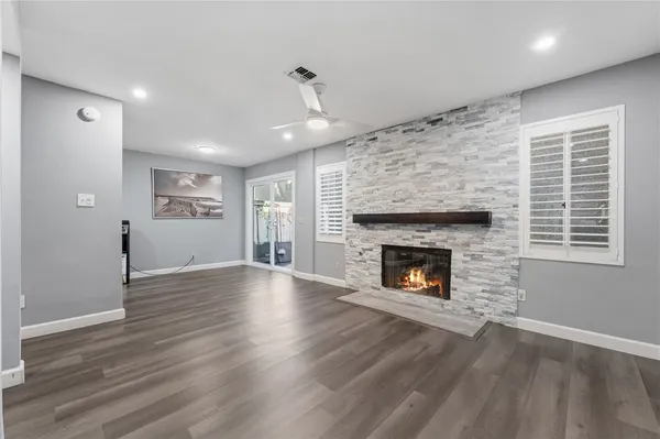 a view of an empty room with wooden floor fireplace and a window