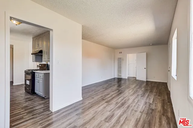 a view of a room with wooden floor and a kitchen