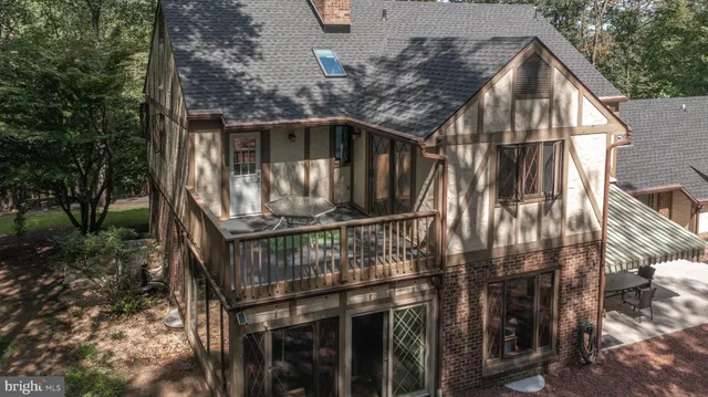 a view of a white house with a yard plants and large tree